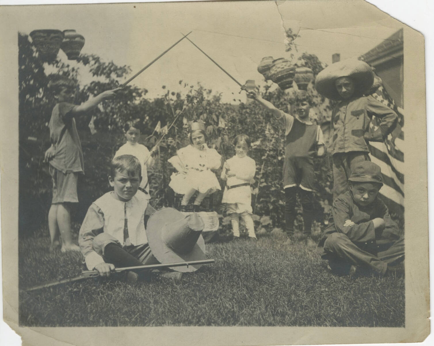 Black and white photograph of a group of children playing, many are wearing costumes.